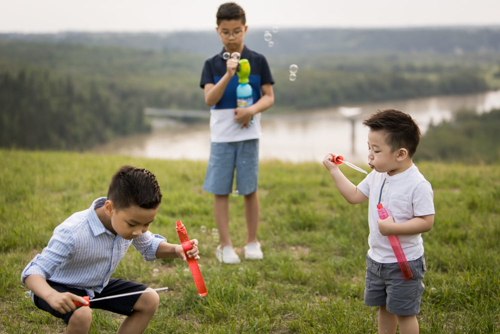 Edmonton outdoor documentary family photography of boys playing with bubble wands in river valley by Paper Bunny Studios