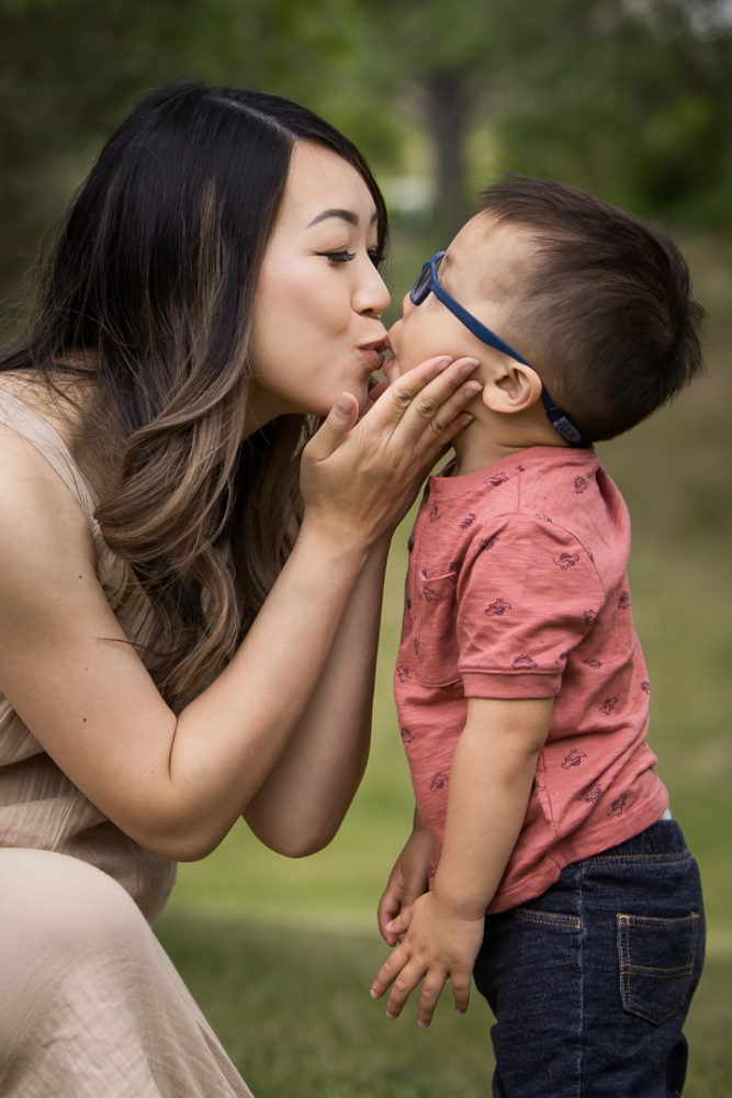 Outdoor family photos of mom kissing little boy by Paper Bunny Studios Edmonton