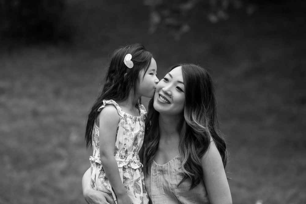 Artistic family photos of daughter kissing mom in black & white by Paper Bunny Studios Edmonton