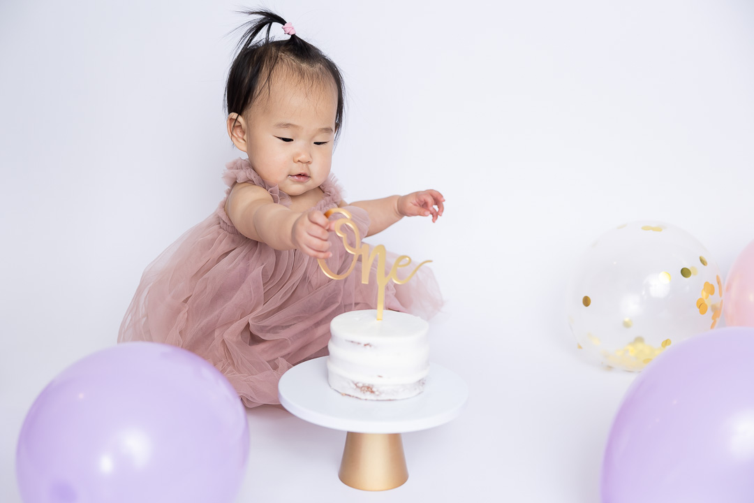 First birthday cake smash photography - baby exploring cake topper by Paper Bunny Studios Edmonton