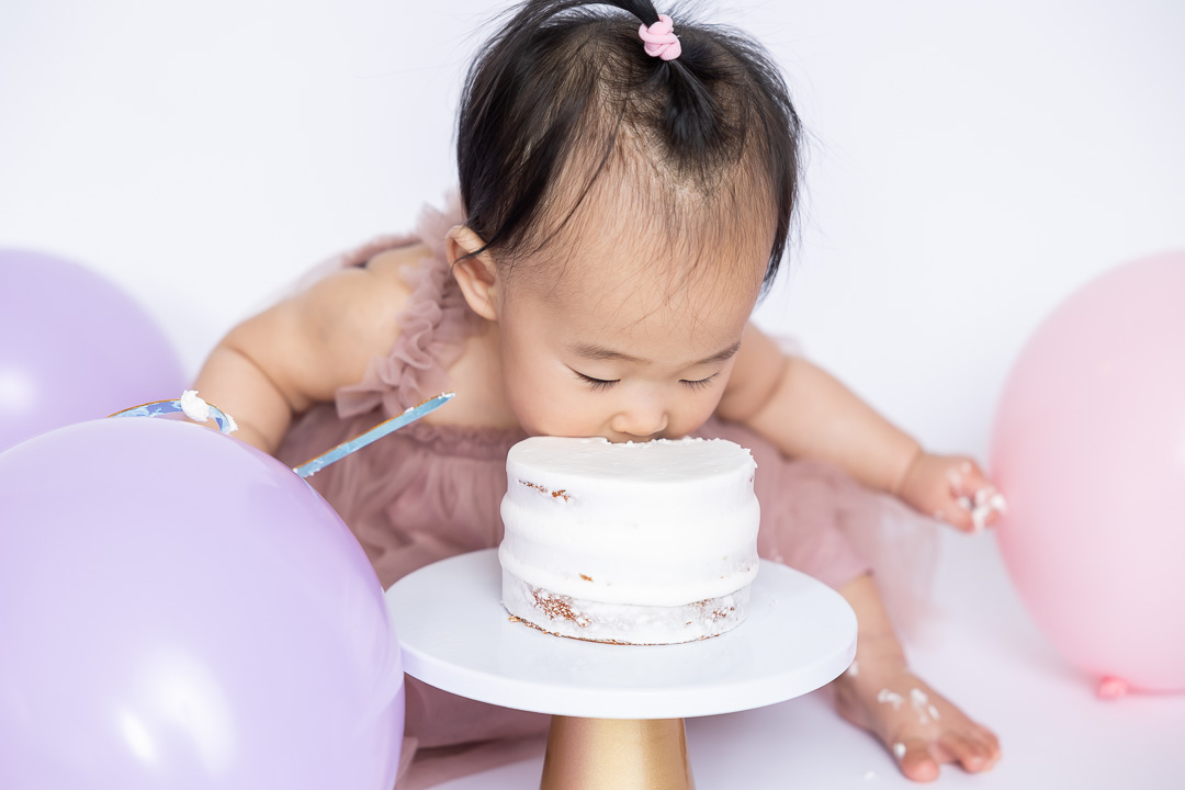 First birthday cake smash photography - baby going face first into cake by Paper Bunny Studios Edmonton