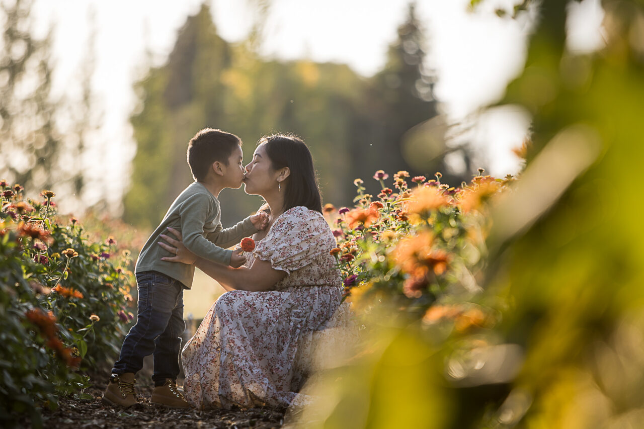 Documentary family photos of mom & son kissing in a flower garden by Edmonton family photographer Paper Bunny Studios