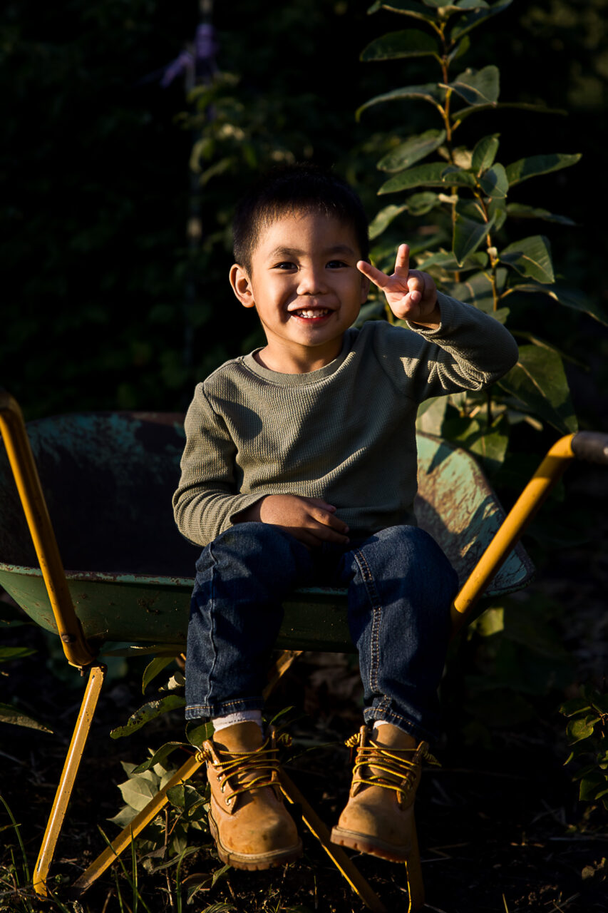 Little boy posing while sat in a wheelbarrow by Edmonton family photographer Paper Bunny Studios