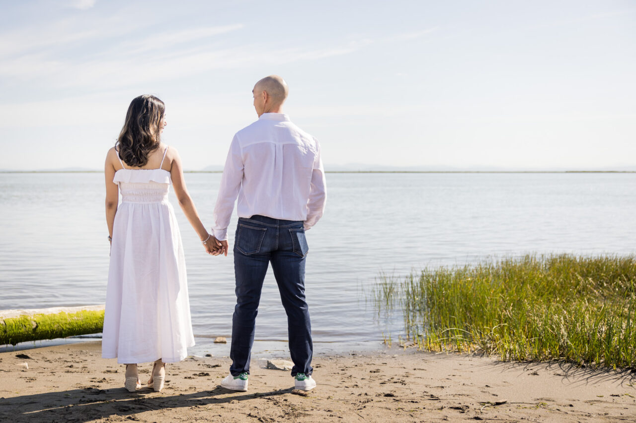 Mom and dad holding hands looking out over ocean by documentary family photographer Paper Bunny Studios