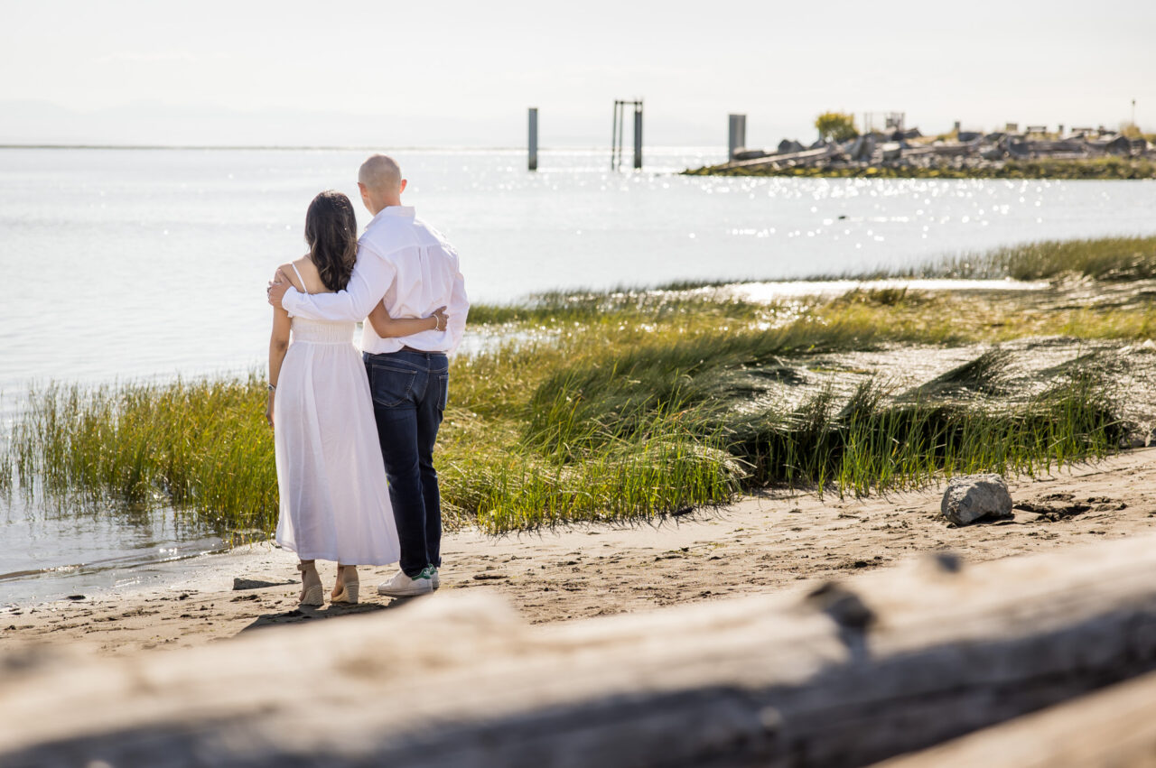Mom and dad embracing as they look out over water by documentary family photographer Paper Bunny Studios