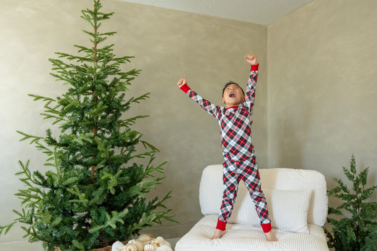 Jumping for joy in Christmas jammes, by Edmonton family photographer Paper Bunny Studios
