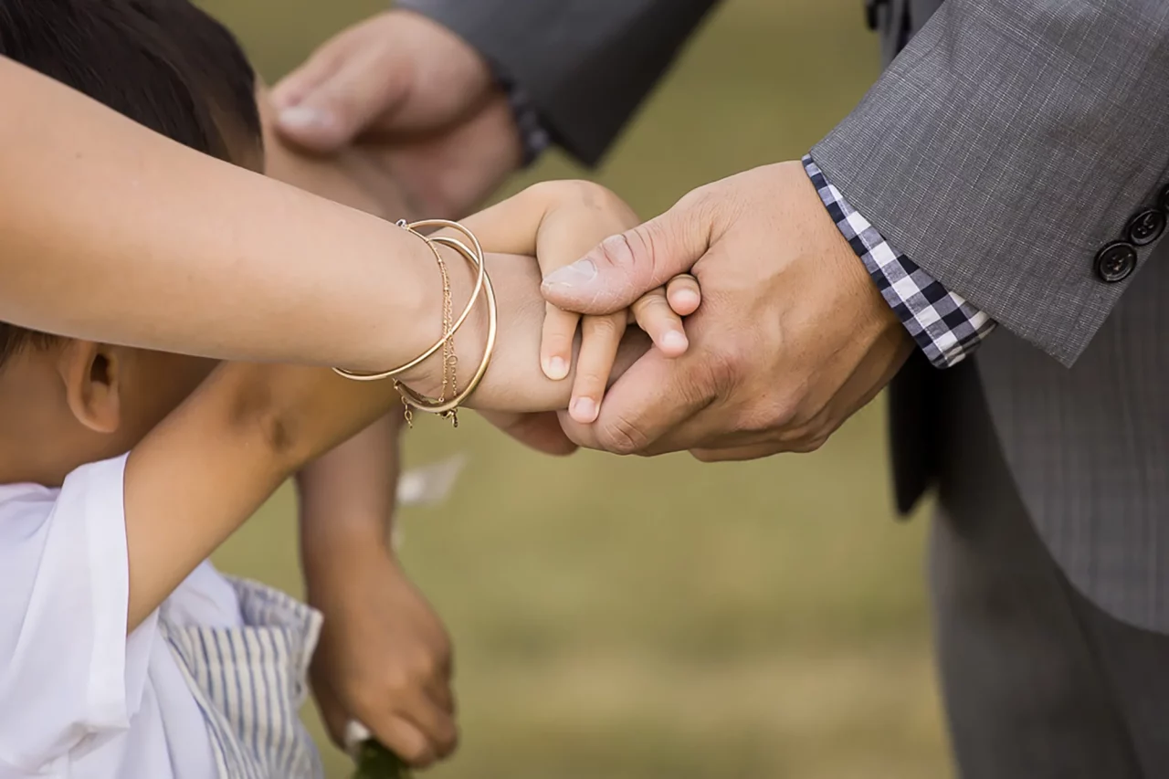 Documentary family photography - detail shot of hands with youngest son adding hand in during vow renewal by paper bunny studios Edmonton