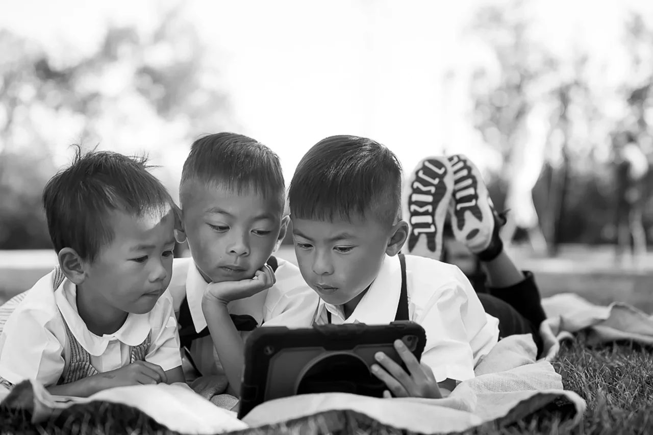 Black & white documentary family photography for vow renewal boys chilling on ipad as parents prep by Paper bunny studios